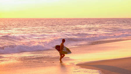 Mazunte, Oaxaca, Mexico - January, 24th, 2018: sufer coming out the water during sunset at Mermejita beachのeditorial素材
