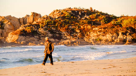 Pochutla, Oaxaca, Mexico - January, 27th, 2018: man walking on the beach at golden hour, Mojon beachのeditorial素材