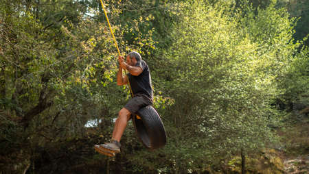 Middle age man on old tire swing treeの写真素材