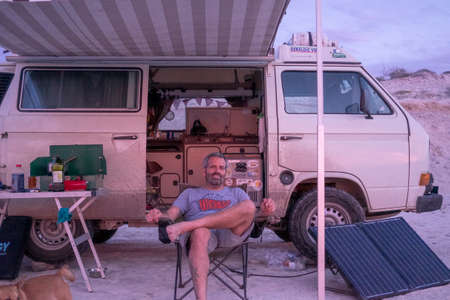 Baja California, Mexico - December 16ht, 2017: single man sit in front of camper van watching the...