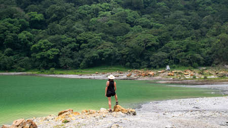 Alegria Lagoon, El Salvador - June, 13th, 2018: girl silhouette over a green lake and lush vegetation.のeditorial素材