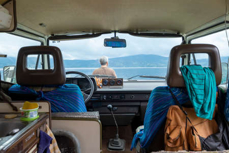Laguna de la Cocha, Colombia - February 9th, 2019: inside camper van parked at the shore with man...