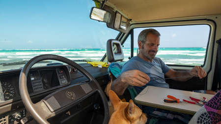 Tulum, Mexico - February 14th, 2018: Inside the classic volkswagen t3 with front seats and table, a man and a dog in front of the sea at the beachのeditorial素材