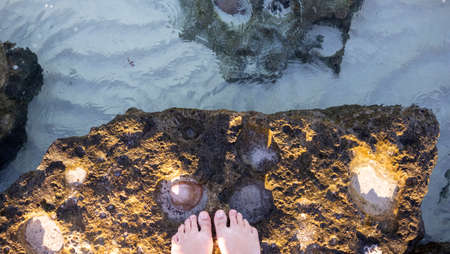 Woman feet in a rock on a paradise beach with crystal blue water