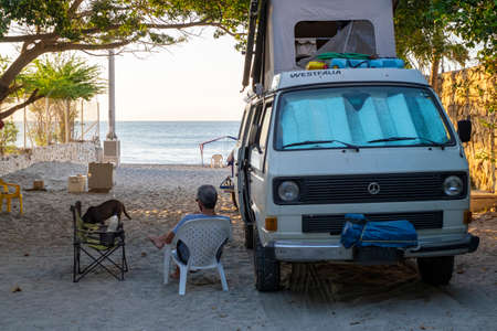Rodadero, Colombia - December 13rd, 2018: Man sit outside a westfalia camper van looking out at the beachのeditorial素材