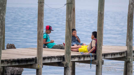 San Pedro La Laguna, Guatemala - May, 23rd, 2018: local kids sit on the wooden pierのeditorial素材