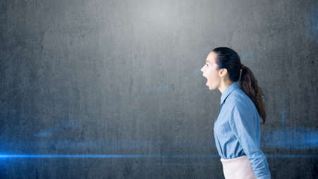 Portrait of young beautiful business woman in the office screaming.の写真素材