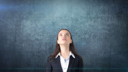 Beautiful businesswoman looking up at copyspace. Standing over navy blue background.の写真素材