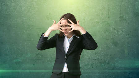 Young business woman dress in black suit and white shirt is hiding, holding her hands near face.の写真素材