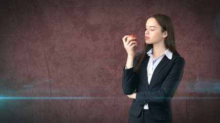 Girl in suit holds bright vibrant apple in hand, symbolising new ideas and fresh concepts or healthy lifestyle in officeの写真素材