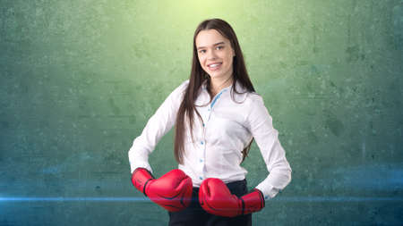 Young beautiful woman dress in white shirt standing in combat pose with red boxing gloves. Business concept.の写真素材