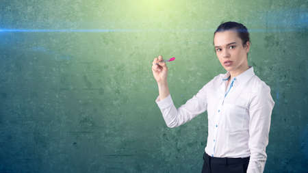 Young beautiful woman in white skirt with pen writing on the screen. Business concept with copyspace.Isolated backgroundの写真素材