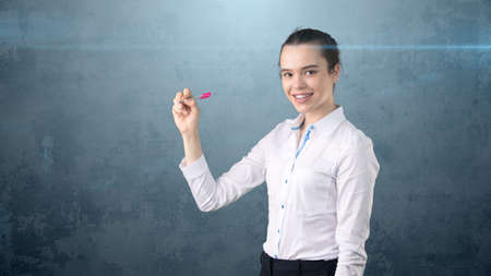 Young beautiful woman in white skirt with pen writing on the screen. Business concept with copyspace.Isolated backgroundの写真素材