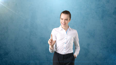 Beautiful business woman in white skirt pushing an invisible button, isolated studio background. Business conceptの写真素材