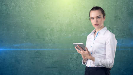 Beautiful woman in skirt with ban looking into a touch pad, isolated studio background with copyspace. Business concept.の写真素材