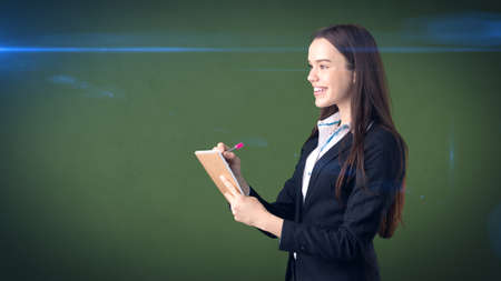 Friendly confident businesswoman writing in her organizer isolated on studio background.の写真素材