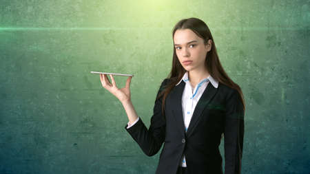 Beautiful serious businesswoman is holding the tray and looking at somethingの写真素材