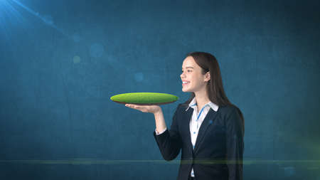 Young woman holding 3D land on the open hand palm with empty copyspace, isolated studio background. Business concept.の写真素材