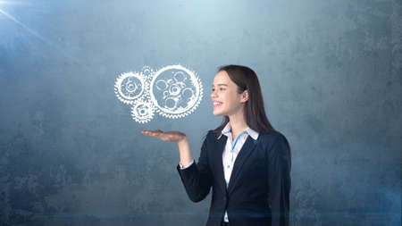 Portrait of woman holding painted watch mechanism on the open hand palm, isolated studio background. Business concept.の写真素材