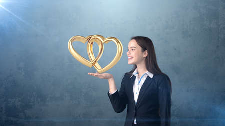 Portrait of young woman holding golden wedding rings on the open hand palm, isolated studio background. Business conceptの写真素材