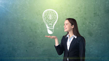 Woman holding painted glowing light with business words and terms on the open hand palm, drawn background. Concept.の写真素材