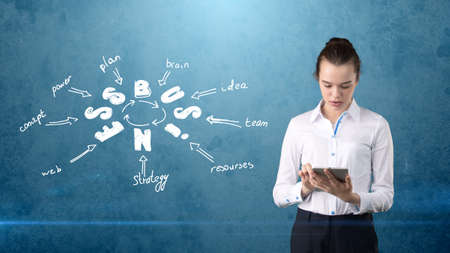 Beauty girl in a suit standing near wall with a business idea sketch drawn on it. Concept of a successful businesswoman.の写真素材