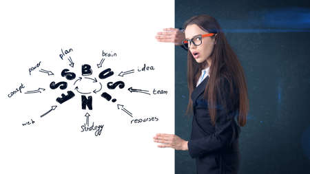 Woman in orange glasses and a suit holding a white leaf with a business sketch drawn on it. Concept of a success.の写真素材