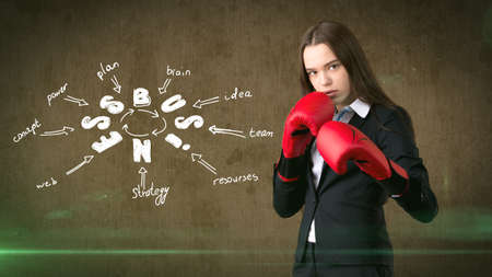 Woman in red boxing gloves standing near wall with a business idea sketch drawn on it. Concept of a successful business.の写真素材