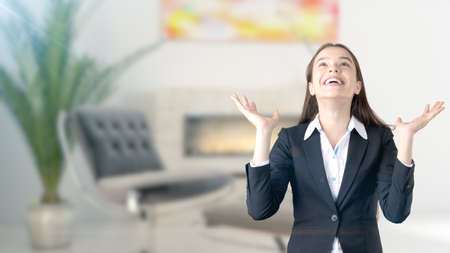 Young beautiful business woman and creative designer standing over blured interior background