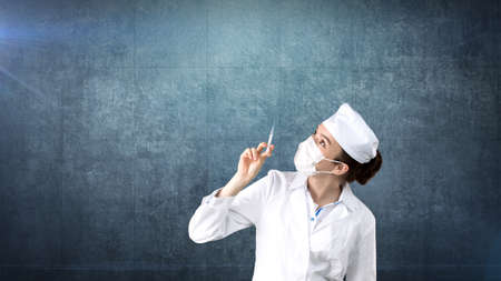 Beautiful medical woman doctor in uniform. Studio painted background. Concept of profitable health care.の写真素材