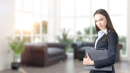 Young beautiful business woman and creative designer standing over blured interior background