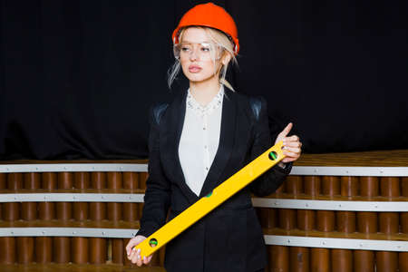 Beautiful blonde businesswoman with application tier at loft office in orange construction helmet...