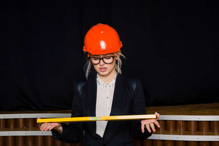Beautiful blonde businesswoman with application tier at loft office in orange construction helmet...