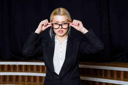 Beautiful blonde businesswoman with puffy lips at loft office in orange glasses and suit. Business...