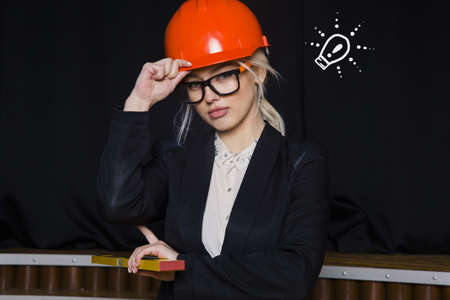 Beauty blonde businesswoman with designer or architect staff is standing against concrete wall with startup sketch on itの写真素材