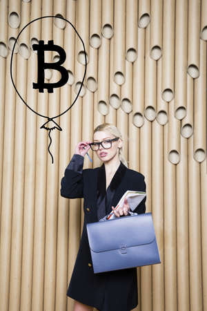 Beautiful blond woman showing standing near bitcoin sketch. Virtual money or btc crush concept. Cryptocurrency.の写真素材