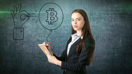 Successful business woman standing near btc. She needs to buy or sell Bitcoin. Concept of virtual criptocurrency.の写真素材