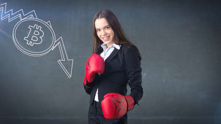 Successful business woman standing near btc logo. She needs to buy or sell Bitcoin. Concept of virtual criptocurrency.の写真素材