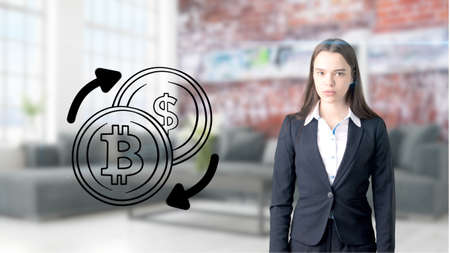 Surprised smiling young woman wearing a suit and looking at a cryptocurrency sketch on a design flat wall. Concept of Bitcoin risk.の写真素材