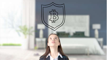 Surprised smiling young woman wearing a suit and looking at a cryptocurrency sketch on a design flat wall. Concept of Bitcoin risk.の写真素材