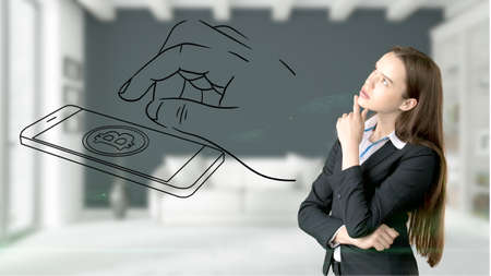 Surprised smiling young woman wearing a suit and looking at a cryptocurrency sketch on a design flat wall. Concept of Bitcoin risk.の写真素材