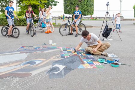 VOLGOGRAD, RUSSIA - July 04, 2016: The young artist draws on the street, on asphalt in the summer. Volgograd, Russiaのeditorial素材