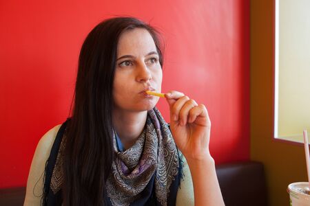 The positive girl the brunette in a scarf is French fries の写真素材