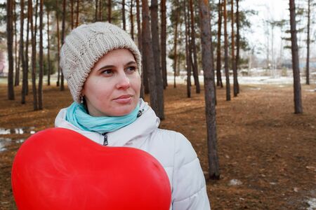 The woman in the middle of trees keeps in warm clothes naduveny the balloon in the form of heartの写真素材