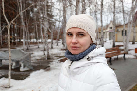 The woman's portrait in the winter on the street in the park among treesの写真素材