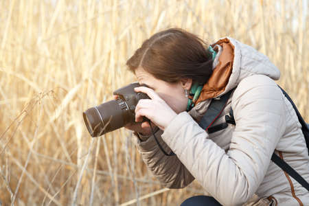 The girl the photographer holds the camera in the middle of dry plants and bushesの写真素材