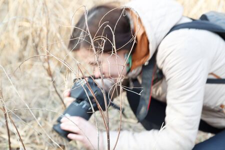 The girl the photographer holds the camera in the middle of dry plants and bushesの写真素材