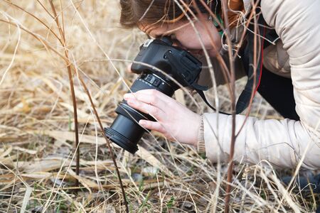 The girl the photographer holds the camera in the middle of dry plants and bushes
