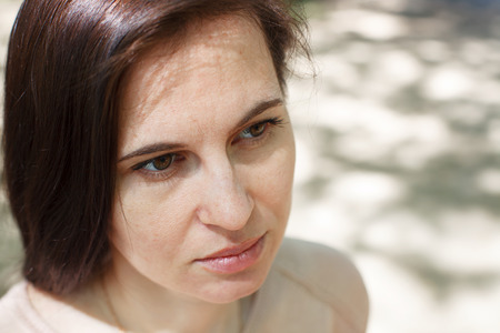 The young girl, the brunette in a pink jacket on the street in the park with a flowing hair, the head, close upの写真素材