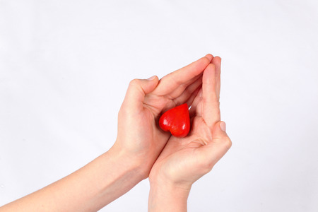 Fingers of hands hold red decorative heartの写真素材